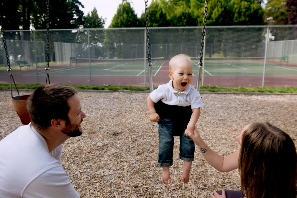 Toddler smiling at family on swings